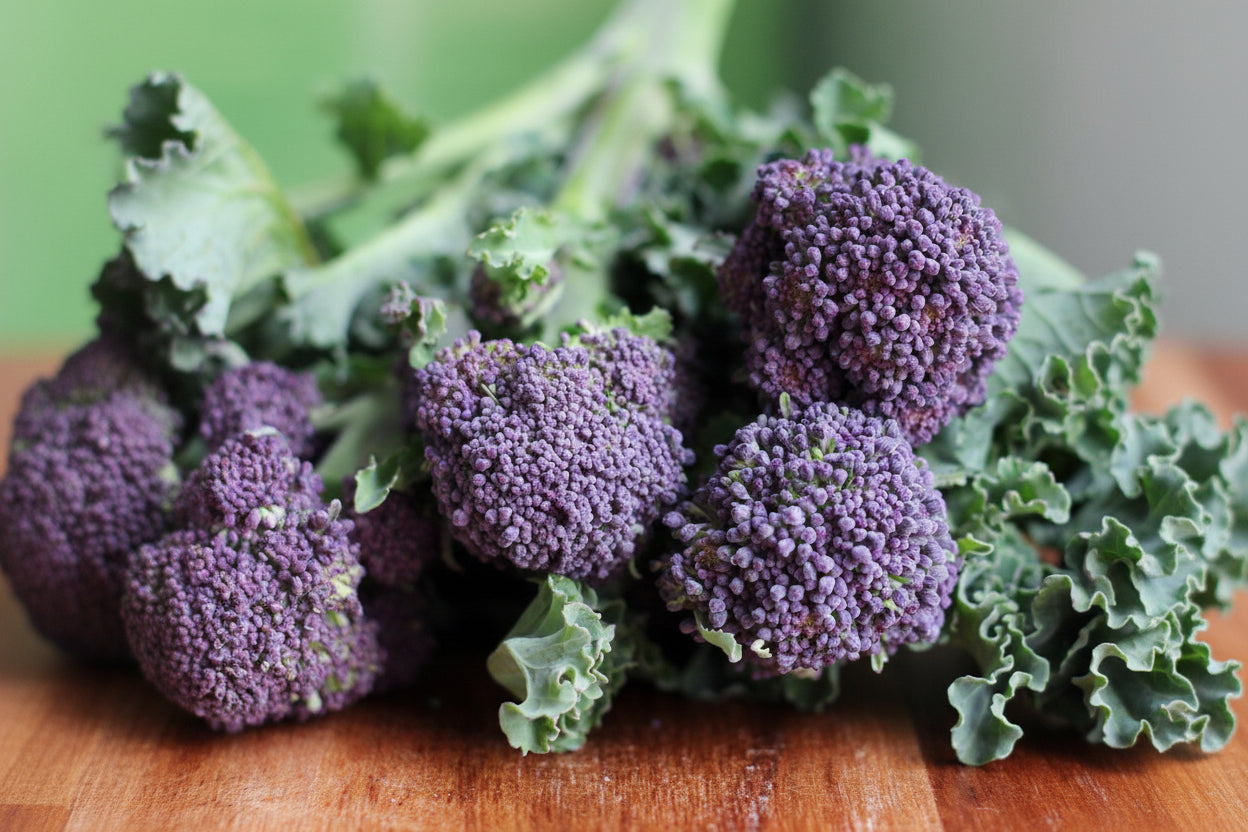 Purple broccoli on a wooden surface with a blurred green background